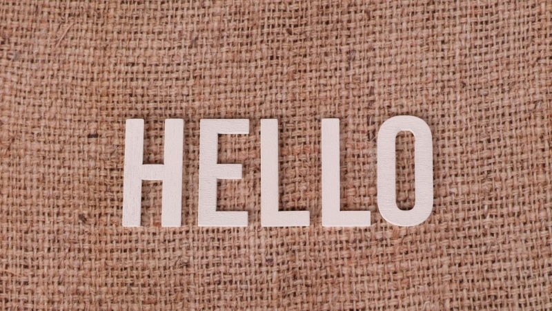 Wooden letters form the word 'HELLO' on a rustic burlap background, offering warm greetings. — Hello world!