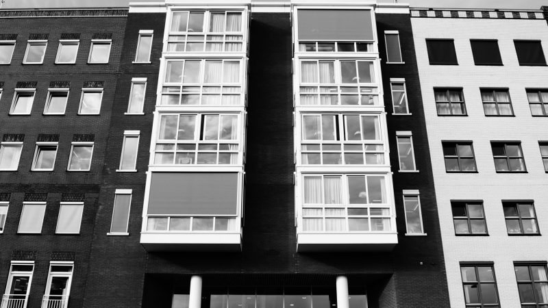 Black and white view of a modern building facade with tall windows. — Realtors - Ways to get the Purchase or Lease