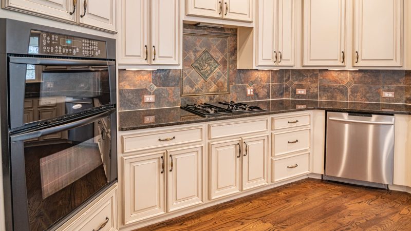 A modern kitchen featuring cabinets, a dishwasher, and a double oven with hardwood floors. — Suggests Ponder during your sear